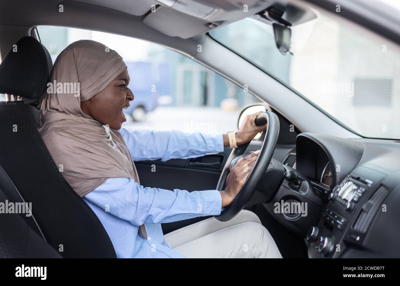 Arrabbiato nero musulmano Businesswoman guida auto, bloccato nel traffico, emotivamente beep Corno Foto Stock