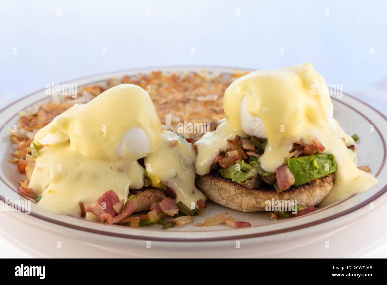 Abbondante pasto di uova abbondanti benedetto accatastato alto con condimenti e gocciolamento con formaggio fuso. Foto Stock