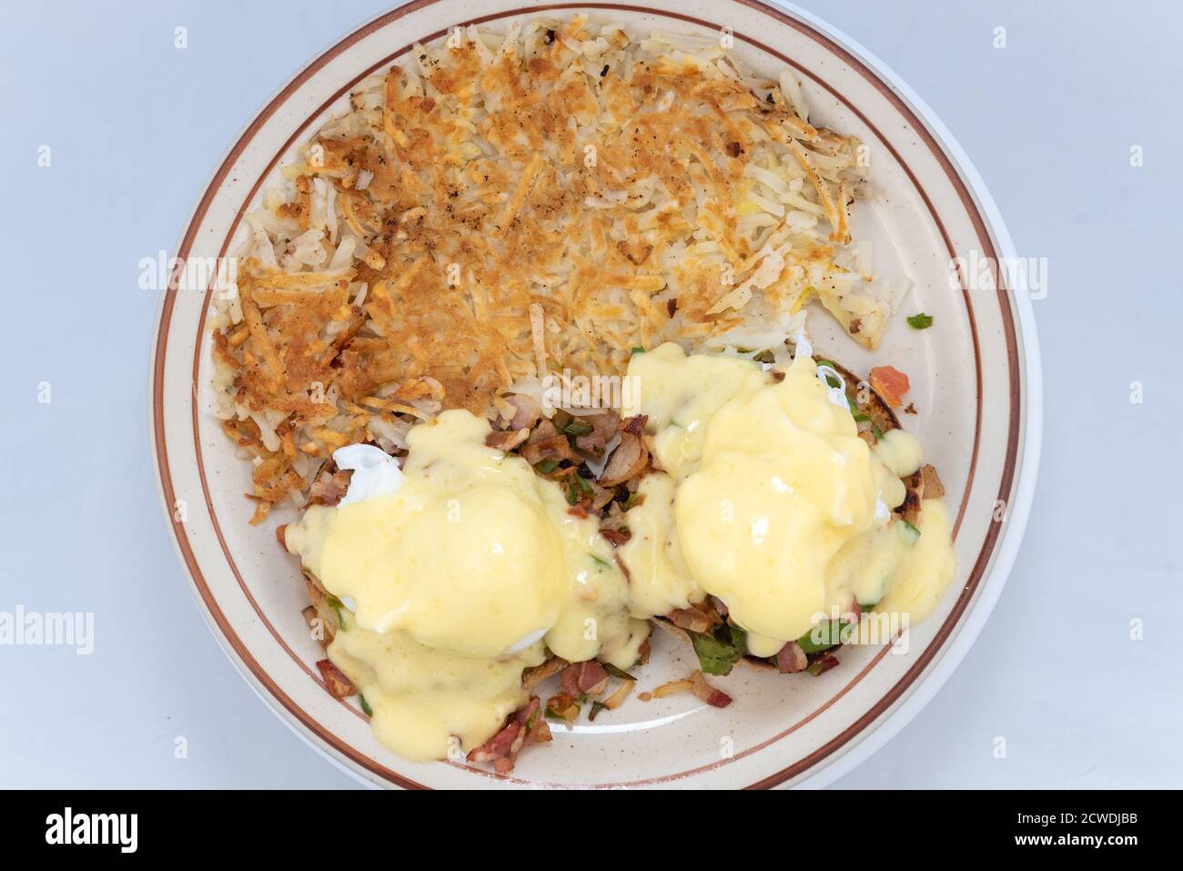 Vista dall'alto di un abbondante pasto servito di uova abbondanti benedetto accatastate con condimenti e gocciolamento di formaggio fuso. Foto Stock