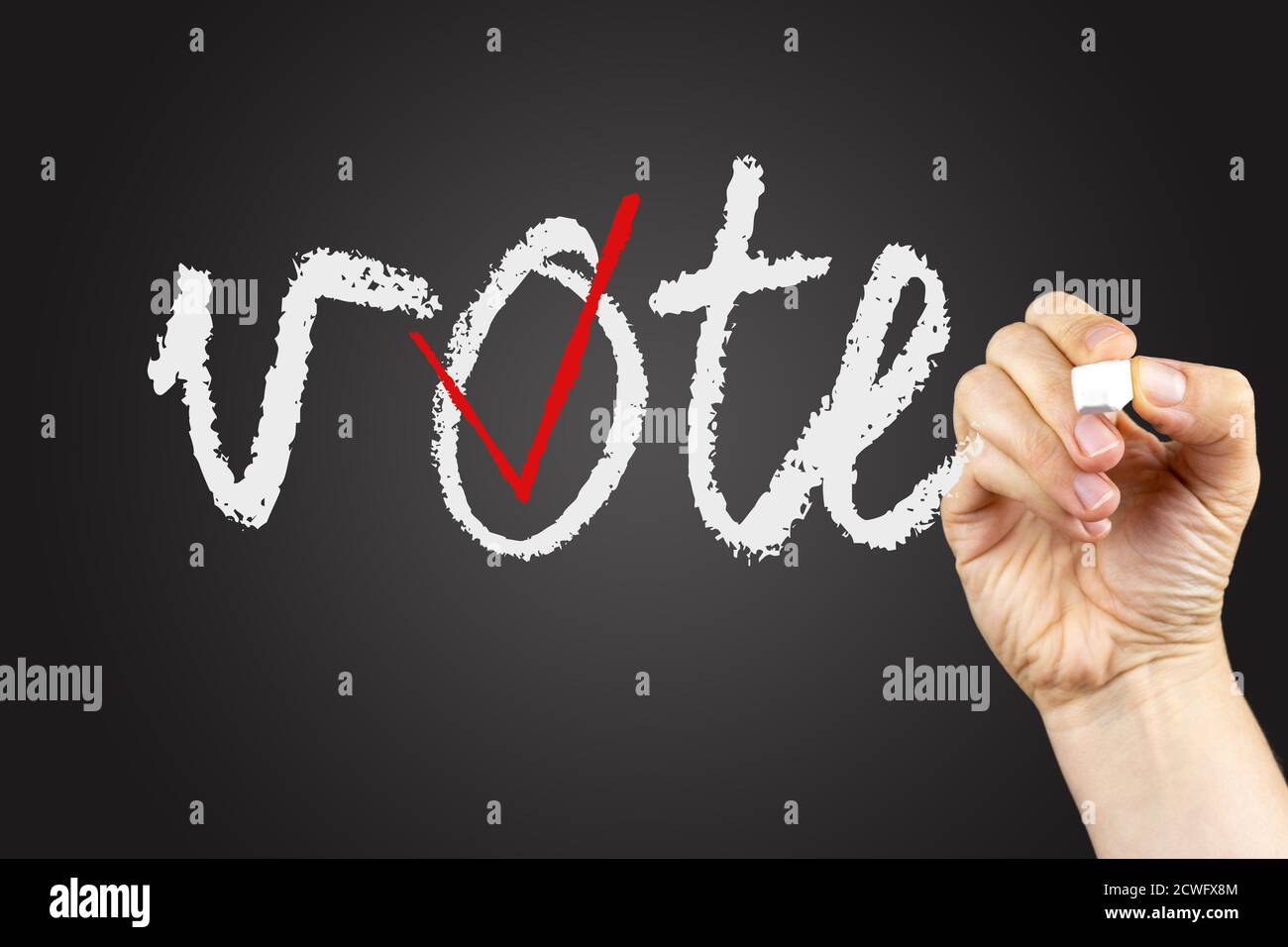 Frase di voto e casella di controllo su una lavagna, scritta con gesso bianco in una mano. Foto Stock