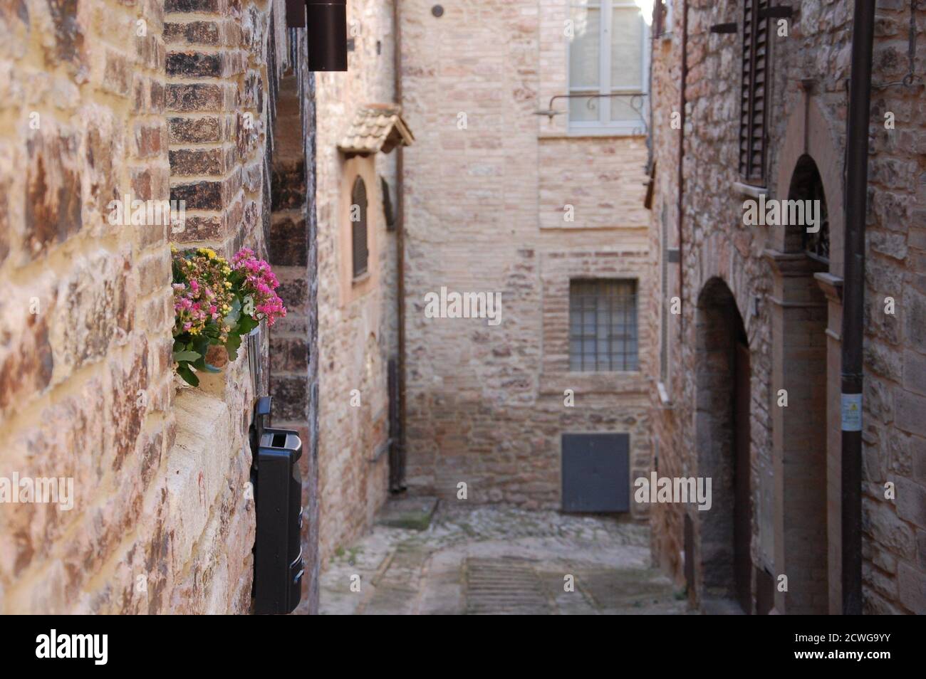 Vista urbana di una strada stretta nella città di Spoleto in Umbria con alti edifici e muratura in mattoni in primo piano non c'è cielo e non ci sono persone Foto Stock