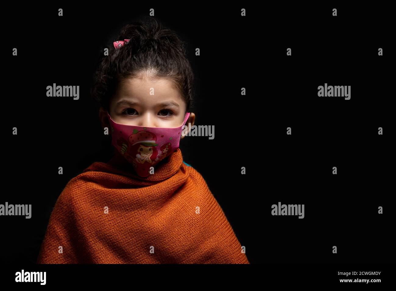 Bambina che indossa una maschera per la protezione da coronavirus epidemico di fronte a sfondo scuro, focolaio di coronavirus e concetto di inquinamento atmosferico Foto Stock
