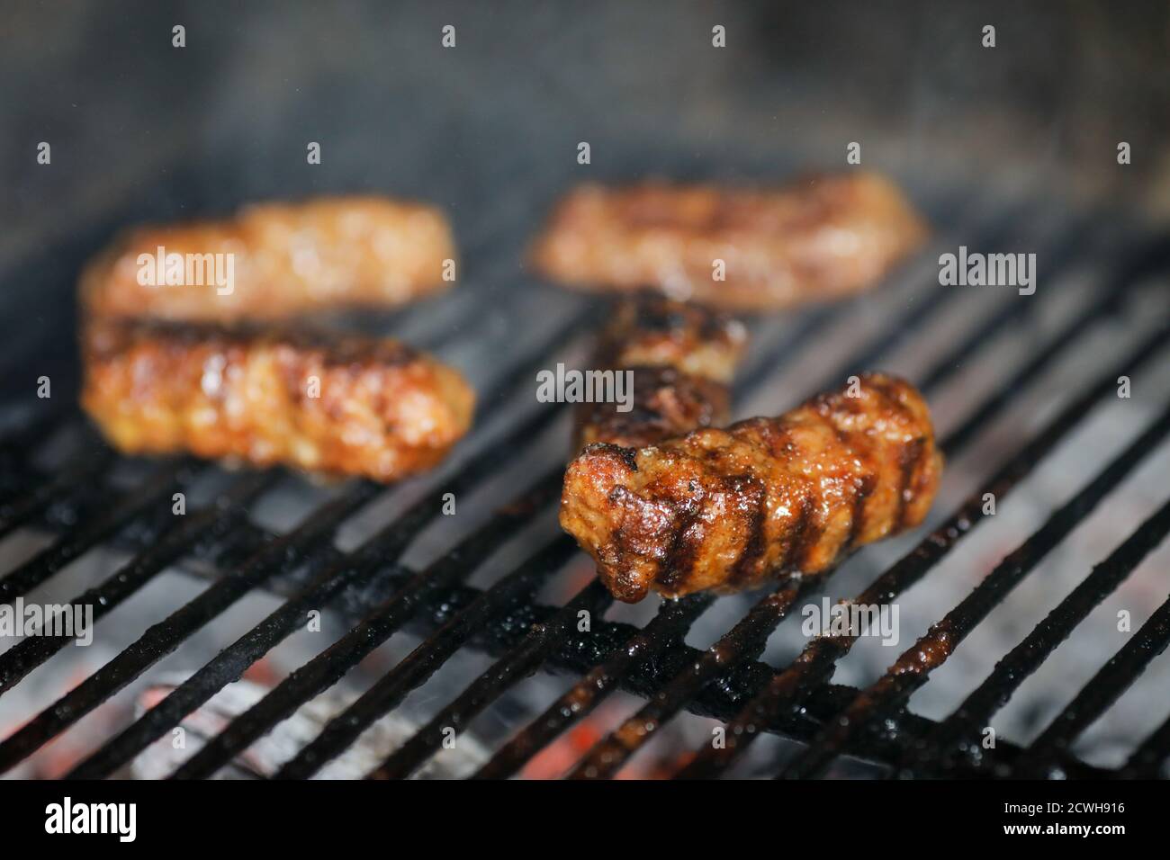Immagine della profondità di campo poco profonda (fuoco selettivo) con mici tradizionali rumeni (mitigei), involtini di carne macinati alla griglia a forma cilindrica sul barbecue Foto Stock