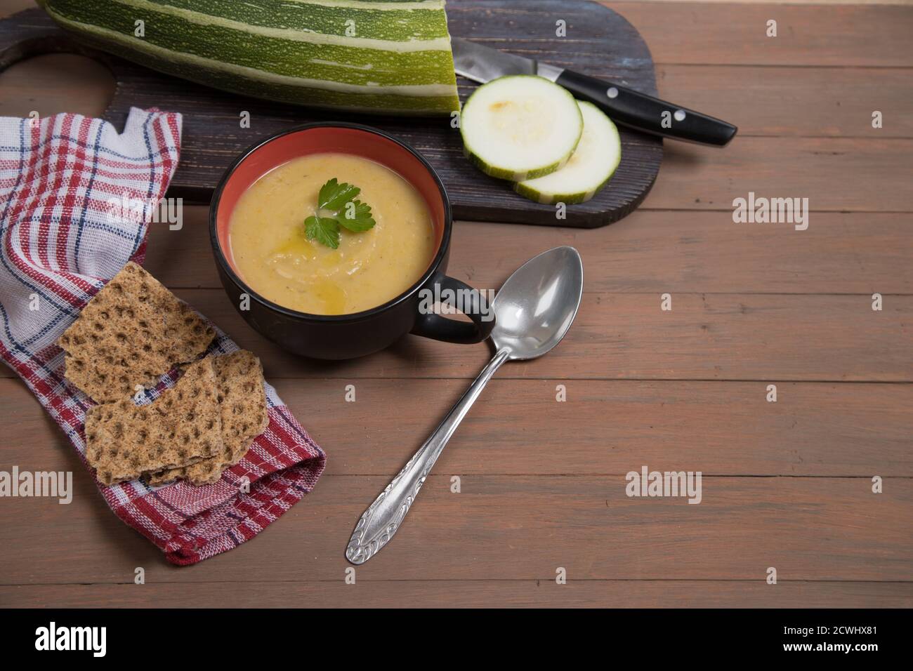 Zucca autunnale zuppa-purè e zucca su uno sfondo di legno marrone, zucchine a fette su un tagliere di legno, grinacchiatori di grano. Inserire uno spazio per la copia Foto Stock