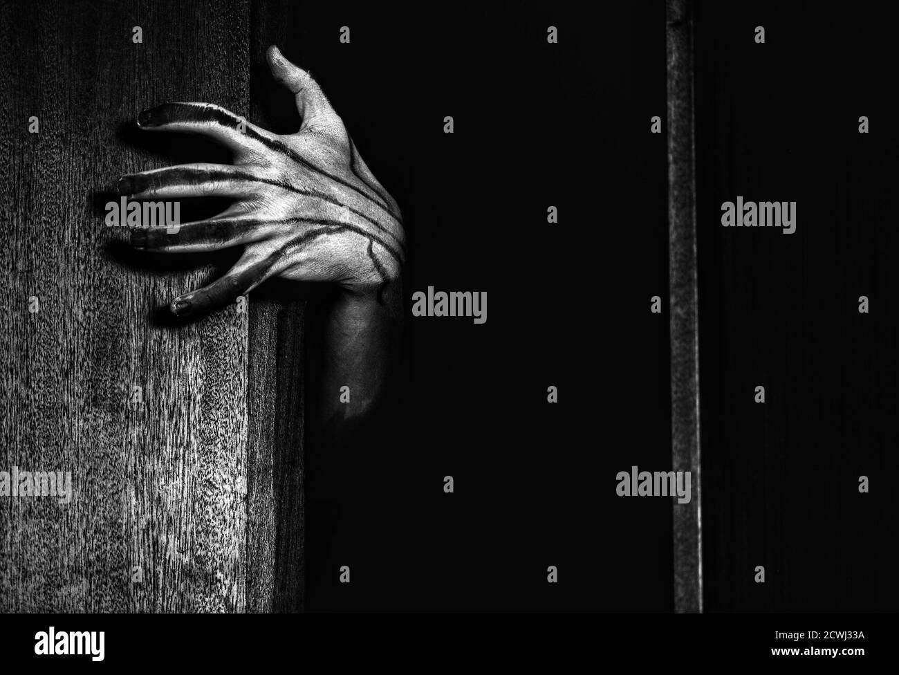 Una fotografia in bianco e nero di una mano creepy che raggiunge da un closet.Horror, spaventoso, scuro. Foto Stock