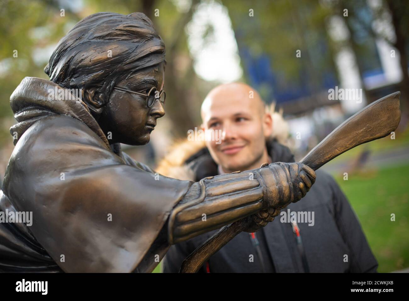 Un uomo guarda la nuova statua di Harry Potter, in Leicester Square, Londra, che raffigura Daniel Radcliffe nel suo ruolo di famoso mago in una scena del primo film, Harry Potter e la pietra del filosofo. Foto Stock