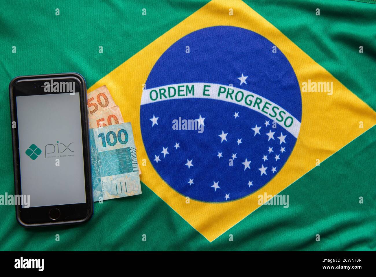 Florianopolis, Brasile. 28/09/2020: Vista dall'alto del logo Pix sugli schermi degli smartphone sulla bandiera brasiliana e sulle banconote. PIX è il nuovo pagamento elettronico brasiliano Foto Stock