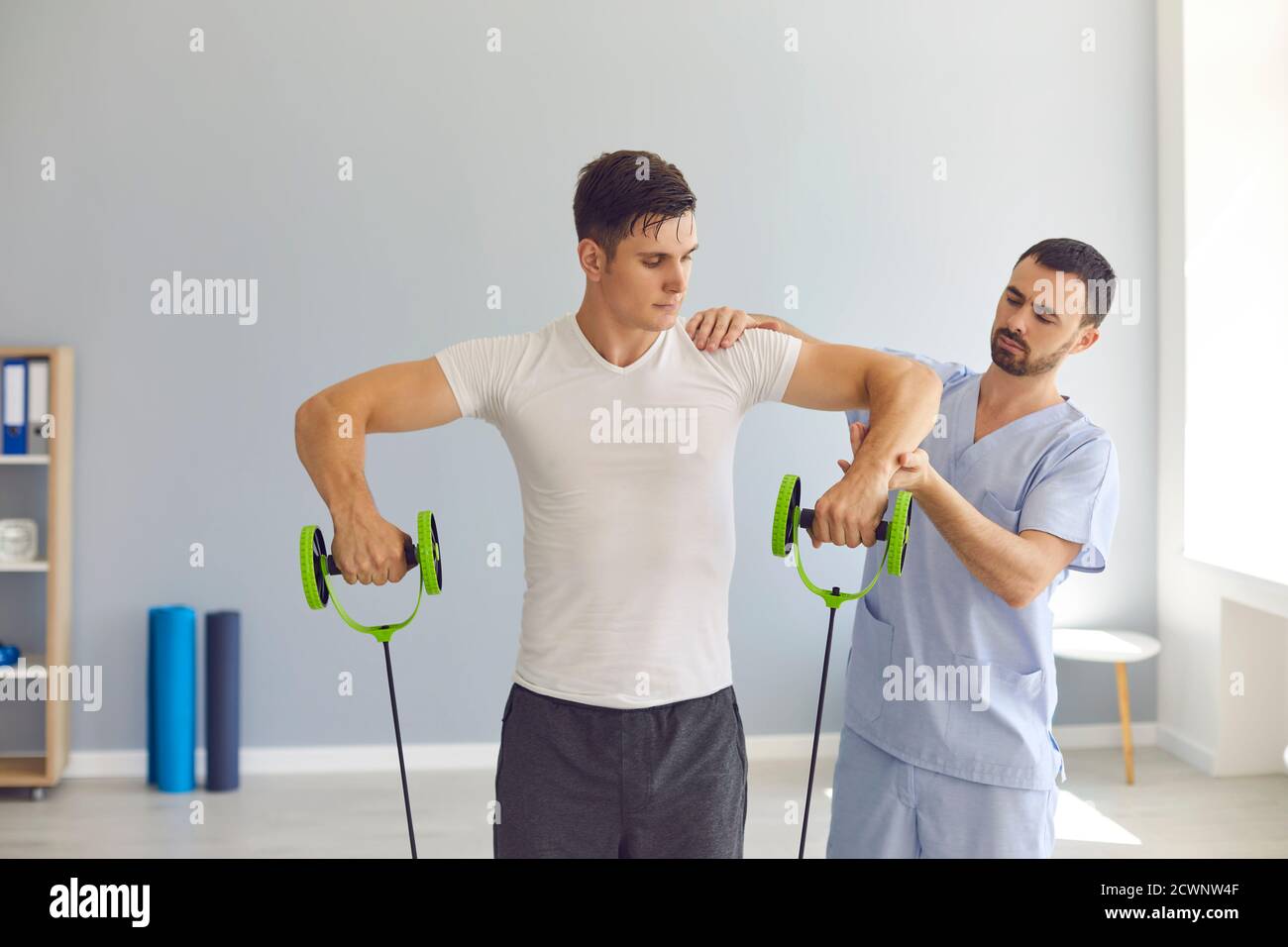 Fisioterapista che aiuta il giovane atleta maschile a recuperare dopo lesioni sportive utilizzando banda di resistenza speciale Foto Stock