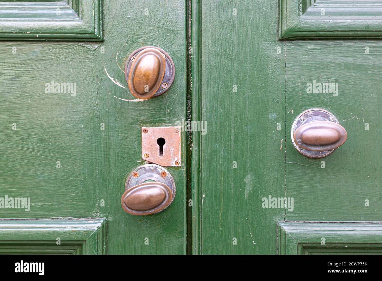 Un primo piano di vecchie manopole di ottoni su una porta di legno verde Foto Stock