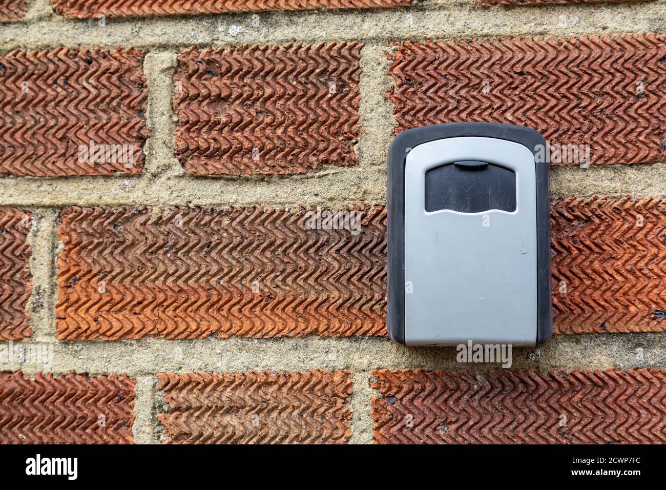 Una cassetta di sicurezza a chiave sul lato di una casa in mattoni, utilizzata per riporre un set di chiavi di ricambio in modo sicuro Foto Stock