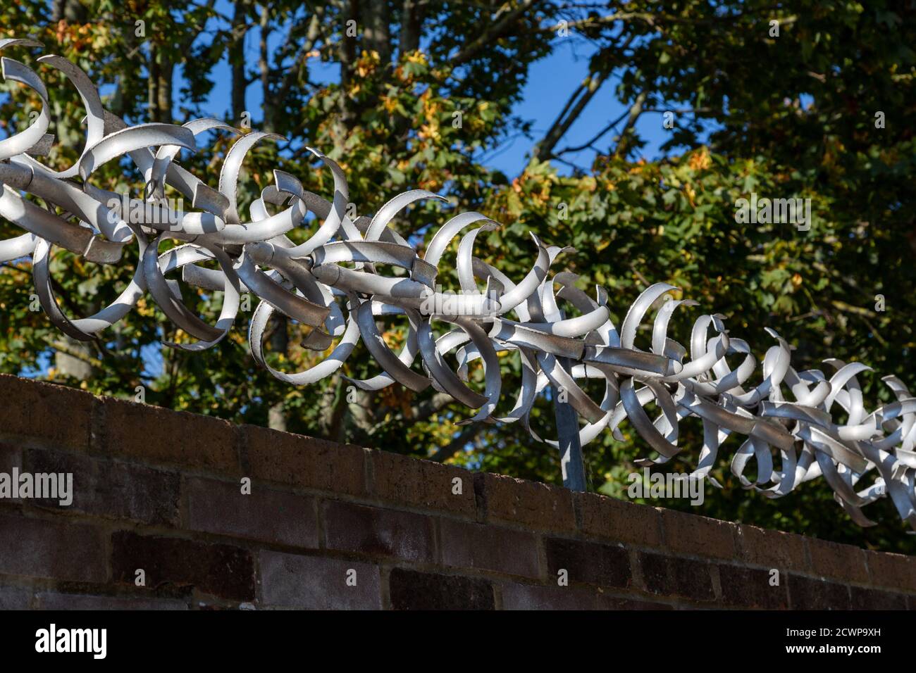 Dispositivo anti-arrampicata sulla parte superiore di un muro di mattoni Foto Stock