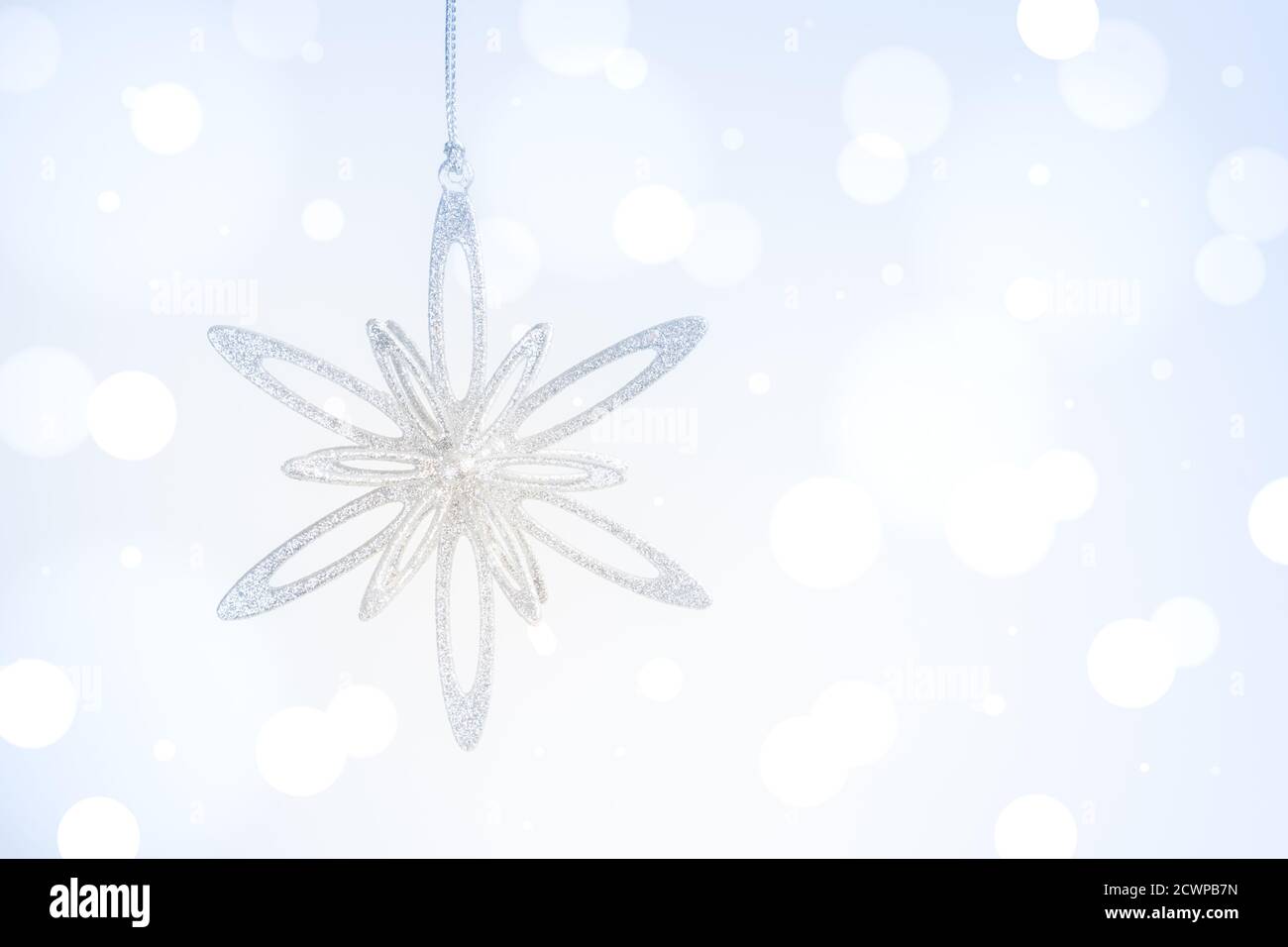 Appendere Natale e nuovo anno brillante stella argento su sfondo blu sfocato. Foto Stock