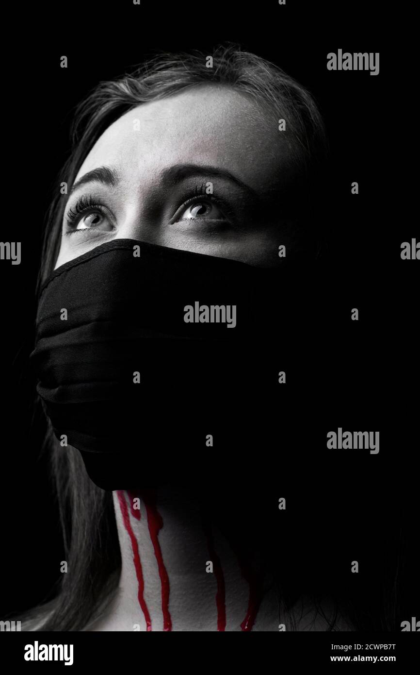 Una donna che indossa una maschera facciale. Sangue che gocciola da sotto la maschera. Colore selettivo in bianco e nero. Foto Stock