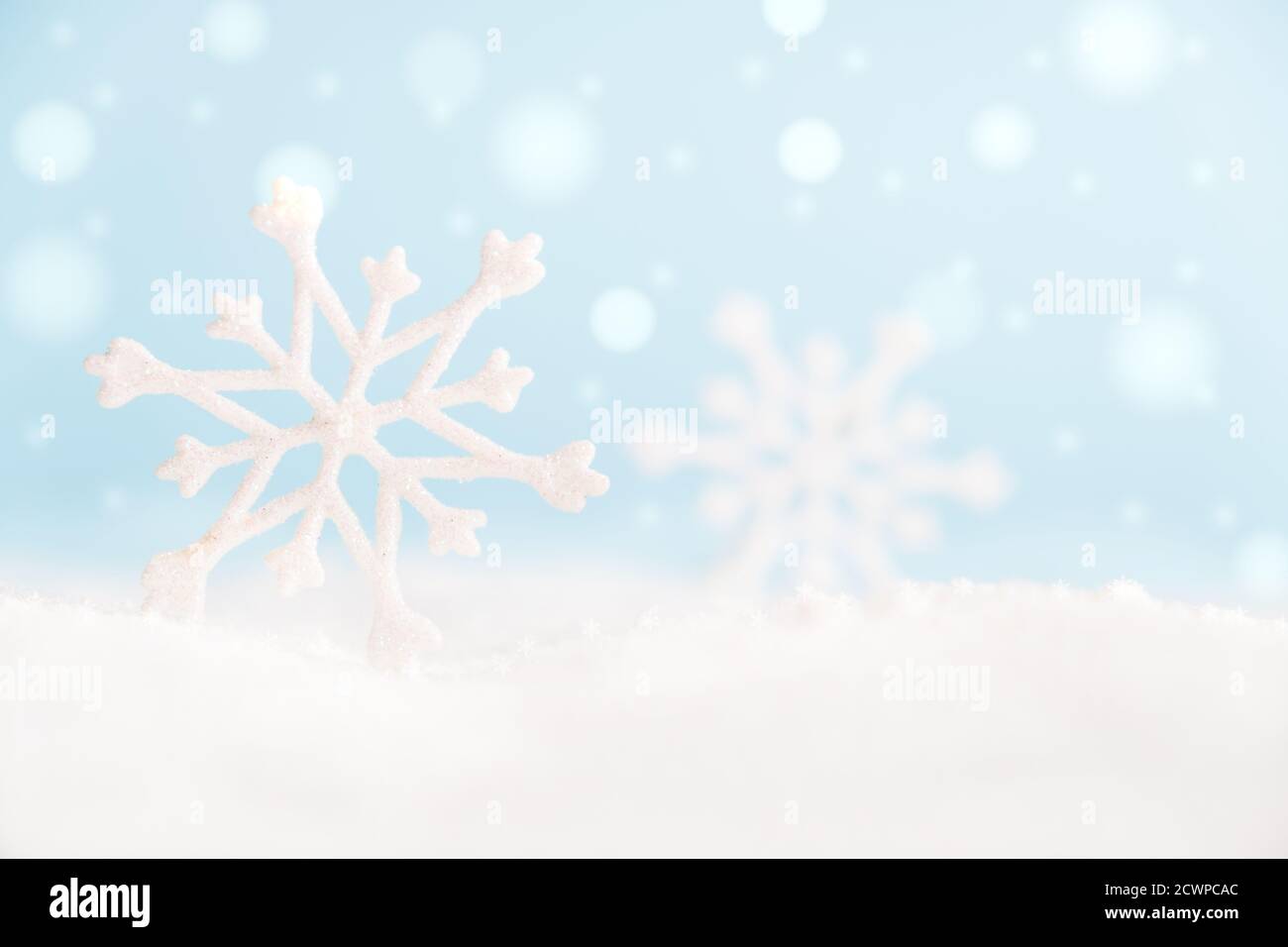 Fiocchi di neve natalizi in superficie con neve e luci sfocate con spazio per la copia. Foto Stock