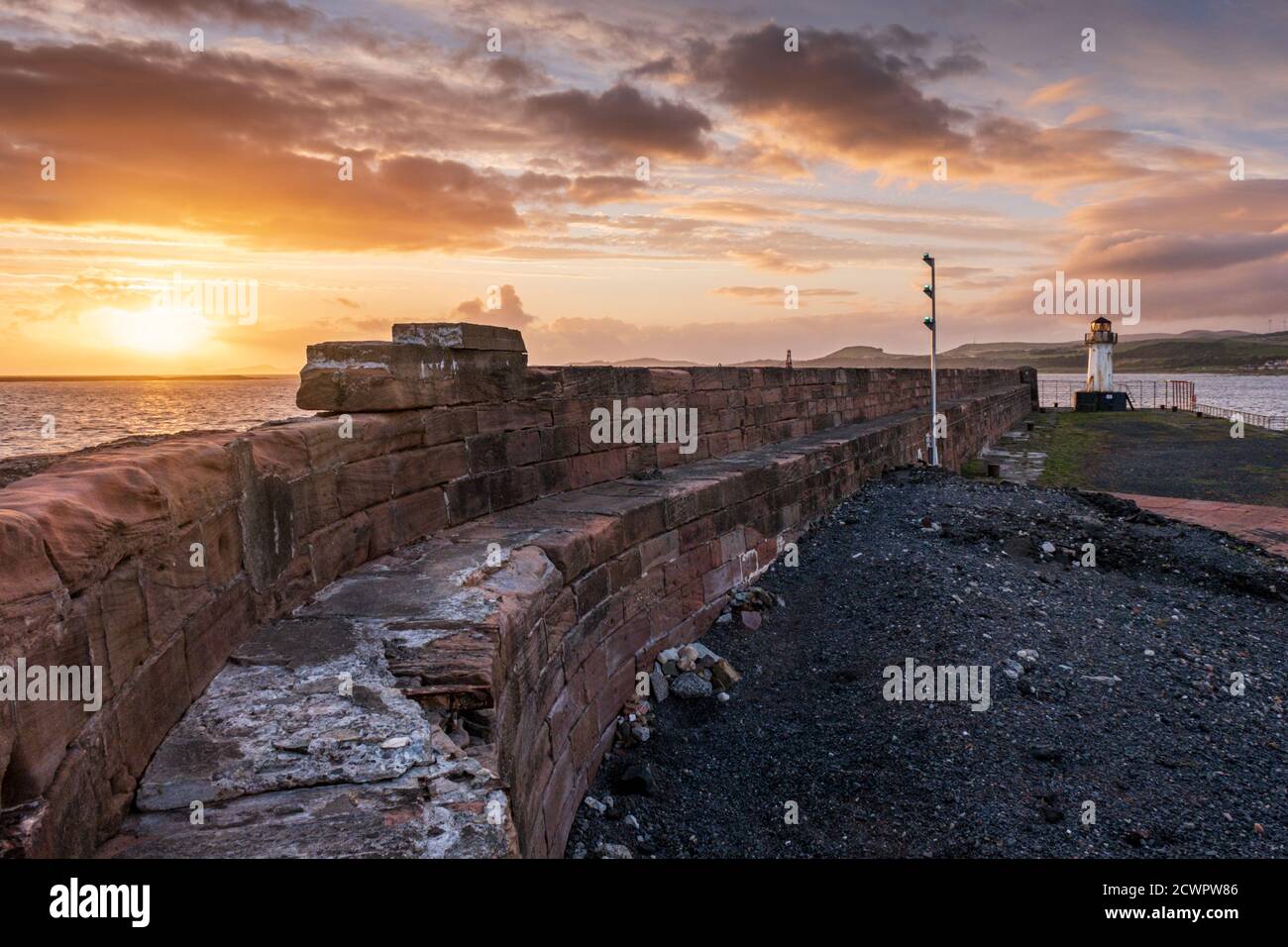 Le mura del porto di Ardrossan e il faro che sorvegliano l'ingresso del porto di Ardrossan sul Firth of Clyde al tramonto, nel Nord Ayrshire, Scozia. Foto Stock