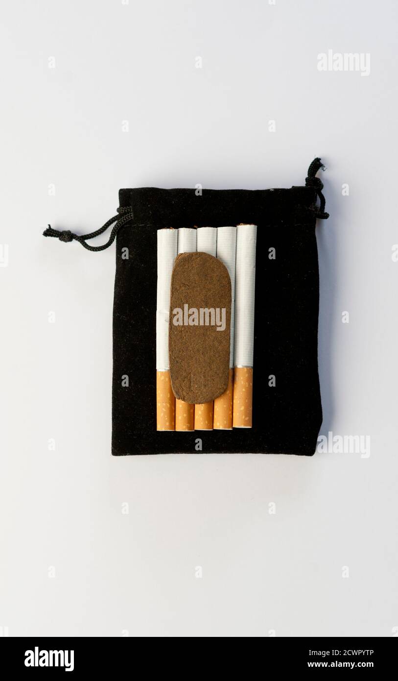 Hashis medico nel Regno del Marocco - CBD pezzo di hashish di cannabis medica marocchina sulla borsa di tabacco superiore, 5 sigari, con sfondo bianco Foto Stock