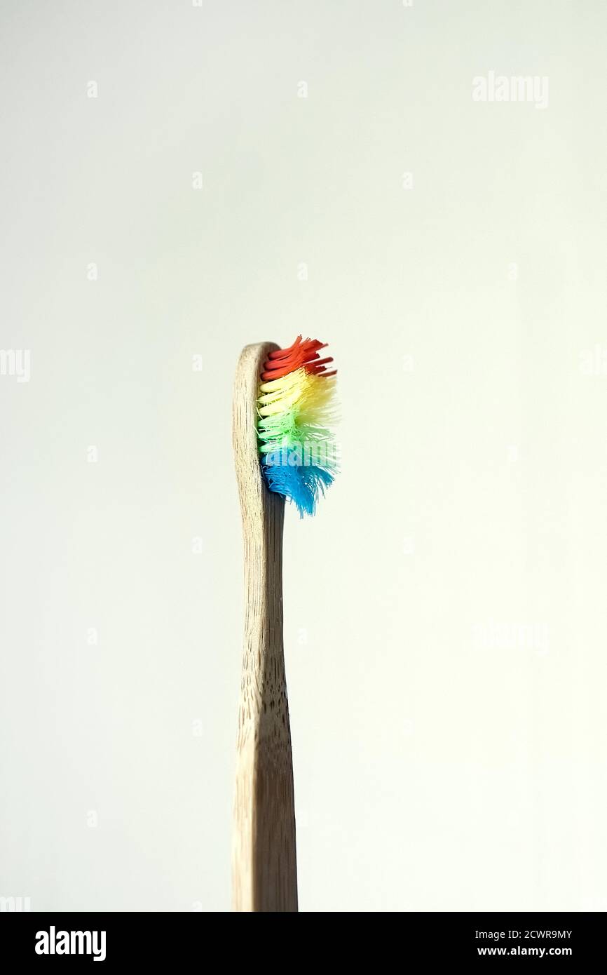 Uno spazzolino di bambù singolo usato con setole di colore arcobaleno Foto Stock
