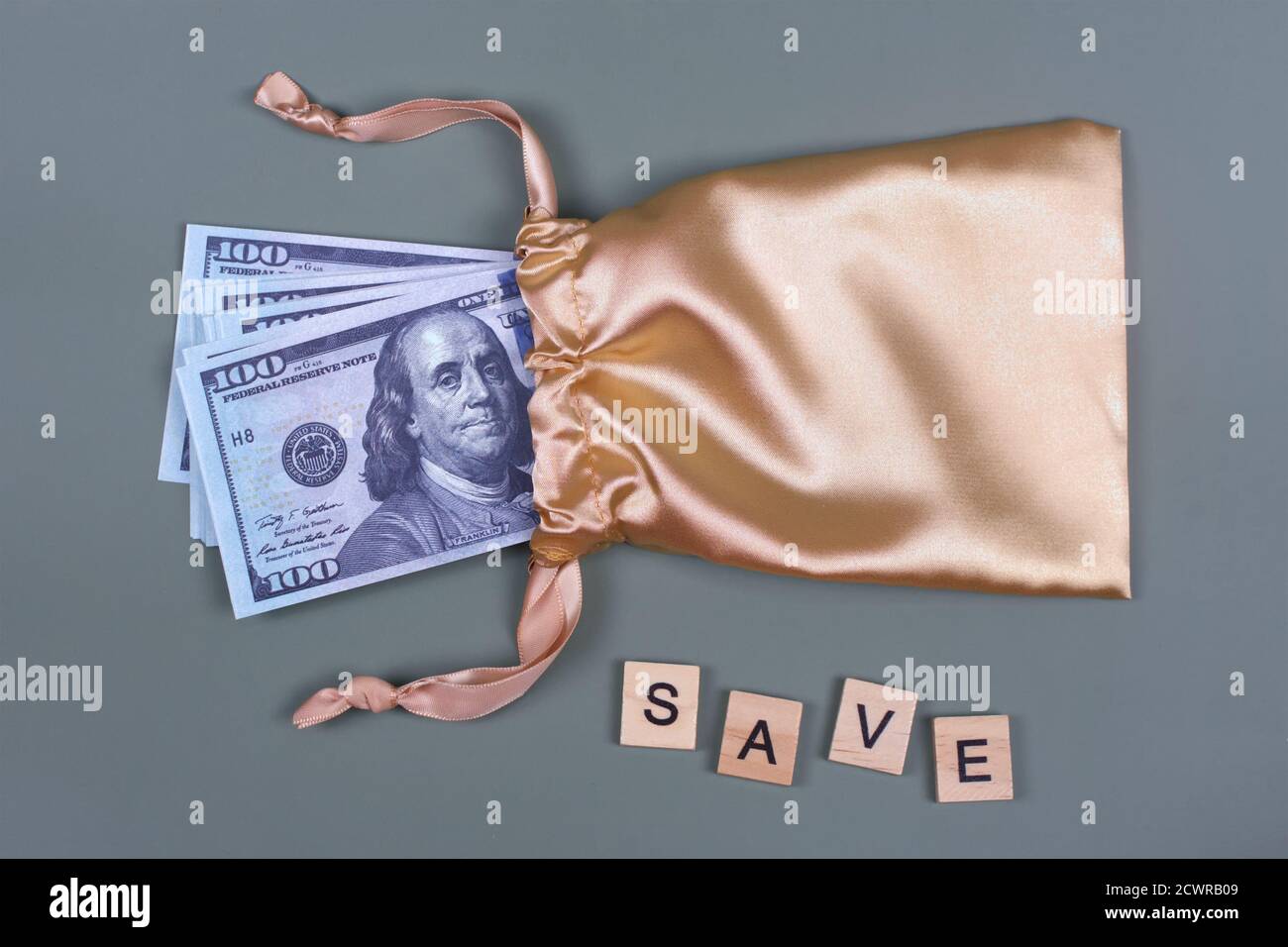Denaro in borsa regalo d'oro con parole DI RISPARMIO. Concetto di risparmio d'investimento. Valuta americana, contanti, bonus, premio monetario, pila di bollette da 100 dollari Foto Stock