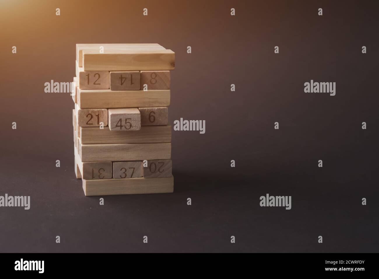 Blocchi di legno ripiegati nella torre con sole su sfondo marrone. Successo, crescita, vittoria, sviluppo o concetto di top rank. Linea di associazione, indi Foto Stock