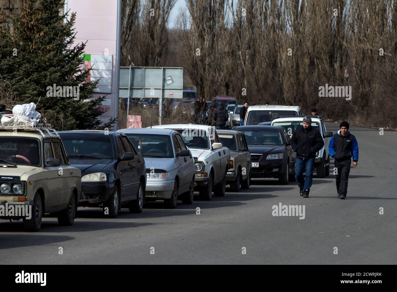 Gli uomini camminano oltre una fila di auto in attesa di attraversare il confine Uspenka tra Ucraina e Russia, a sud-est da Donetsk, 15 marzo 2015. REUTERS/Marko Djurica (UCRAINA - Tags: POLITICA CIVILE SCATENARE IL TRASPORTO DEI CONFLITTI) Foto Stock