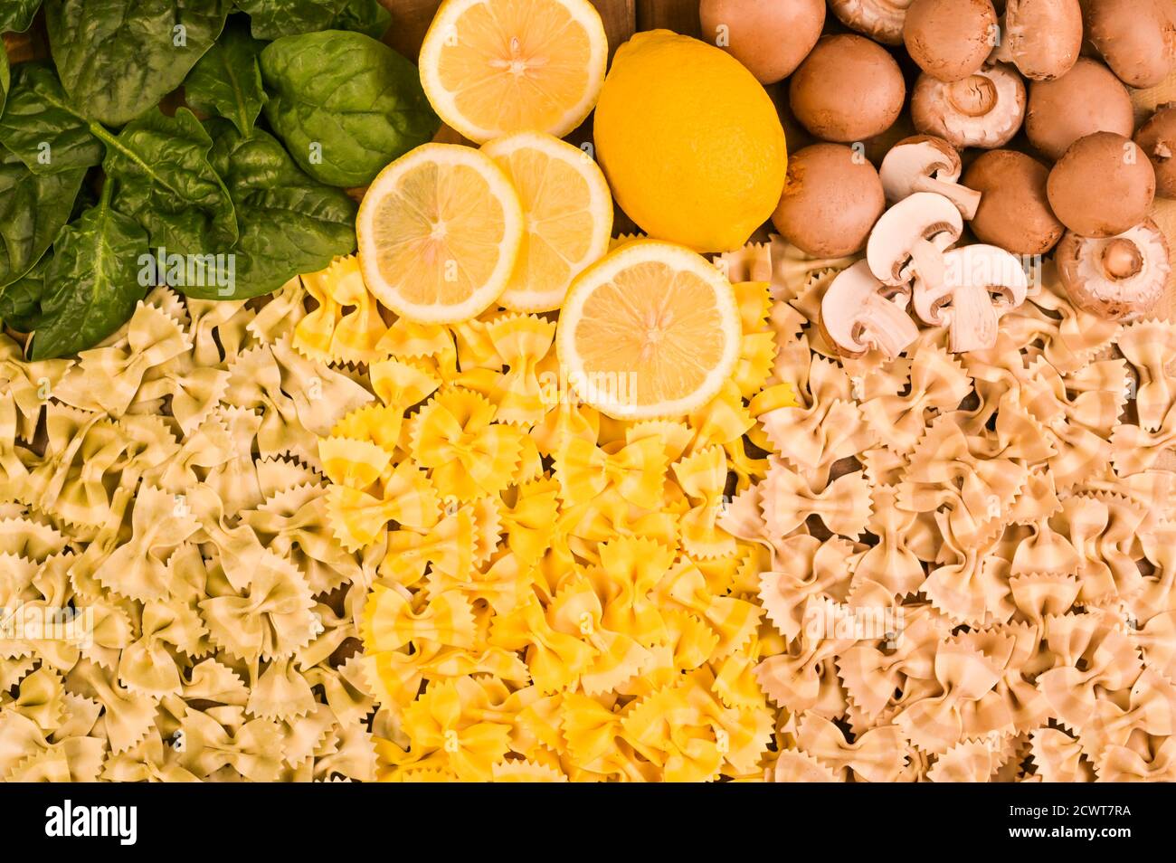 Pasta multicolore con spinaci, funghi e limone. Cucina tipica del sud Italia. Pasta secca alla farfalla con sapori diversi su sfondo ligneo. Foto di alta qualità Foto Stock