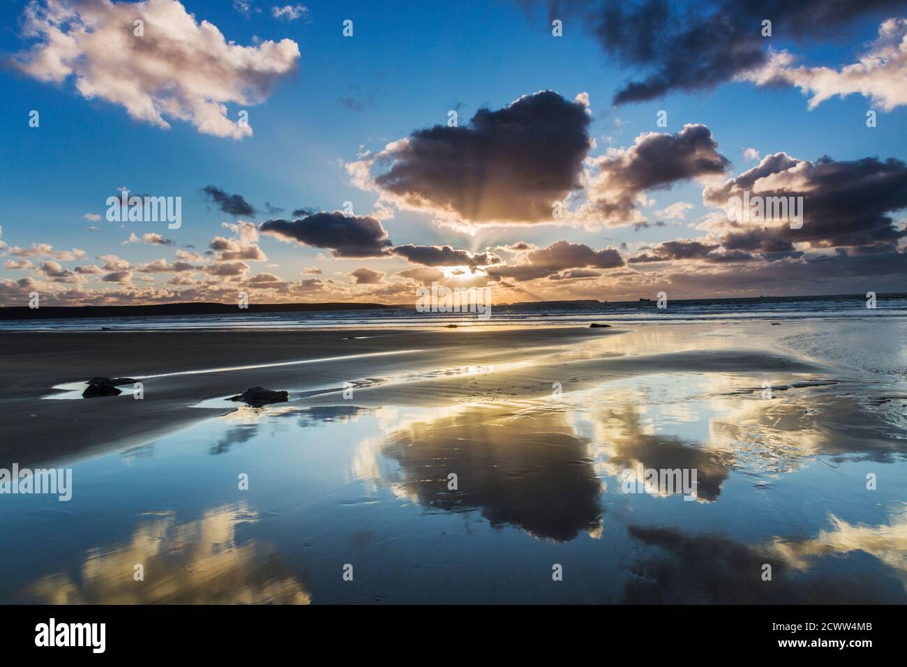 Il cielo al tramonto si riflette nelle sabbie bagnate del spiaggia sotto Foto Stock