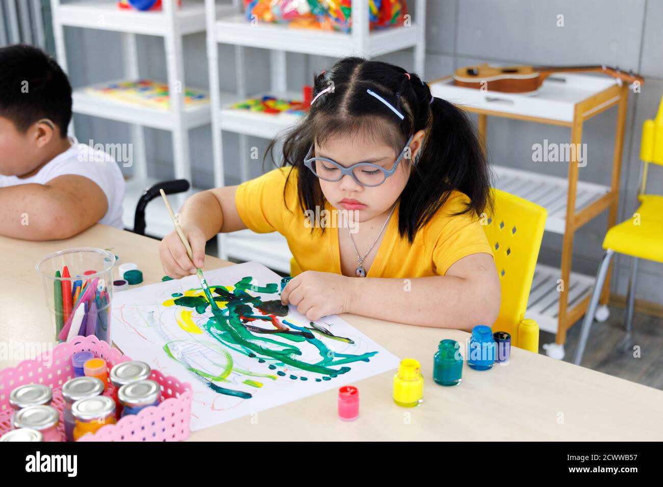 Ragazza asiatica con sindrome di Down pittura in classe d'arte a scuola. Concetto di apprendimento per bambini disabili. Foto Stock