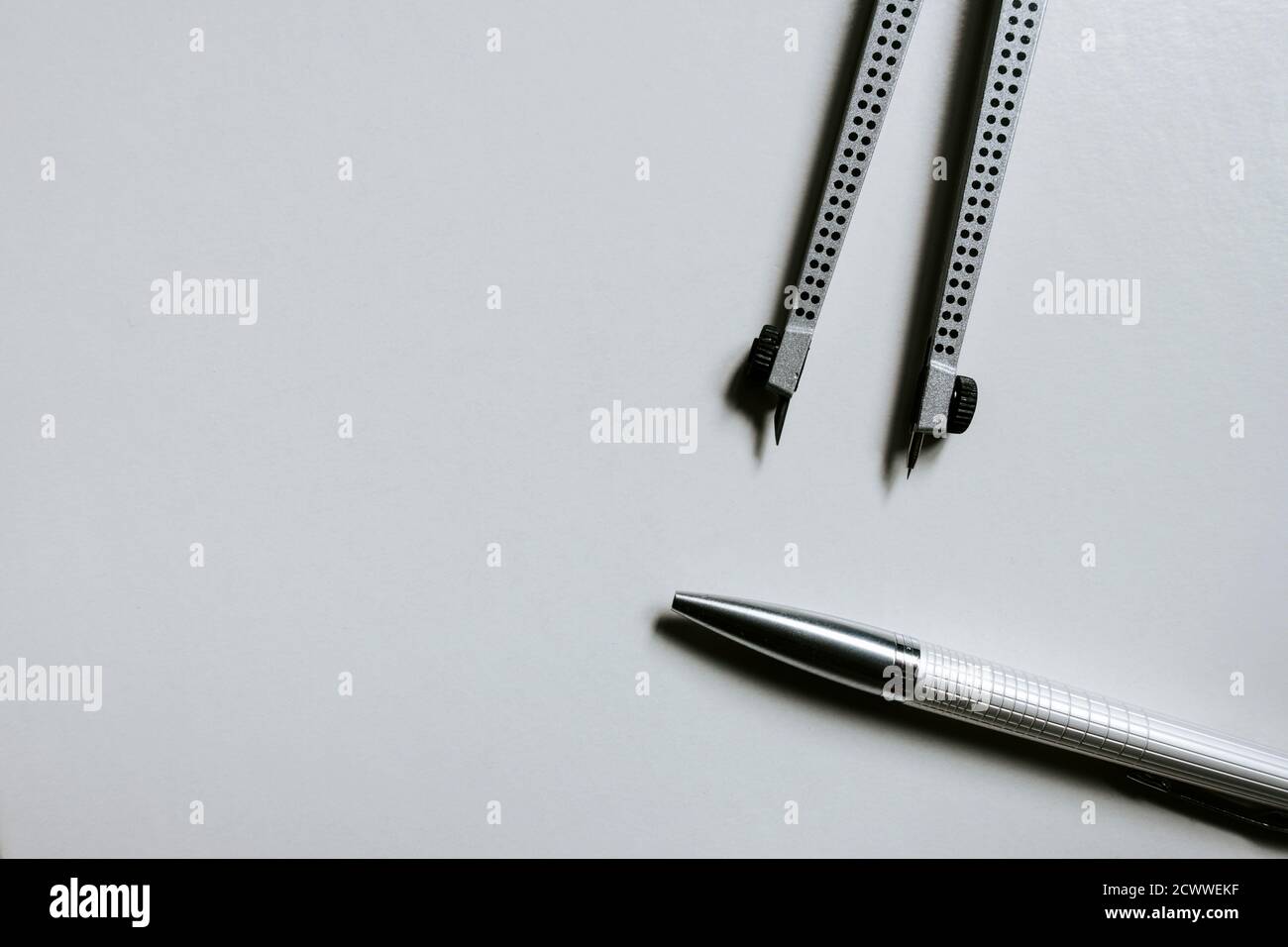 Un paio di bussole e una penna su sfondo bianco Foto Stock