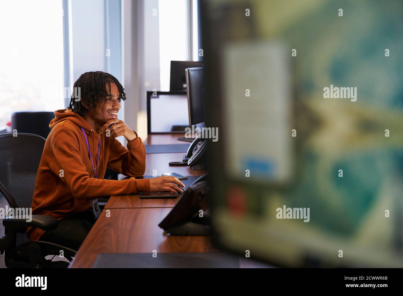Sorridente giovane uomo d'affari che lavora al computer in ufficio Foto Stock