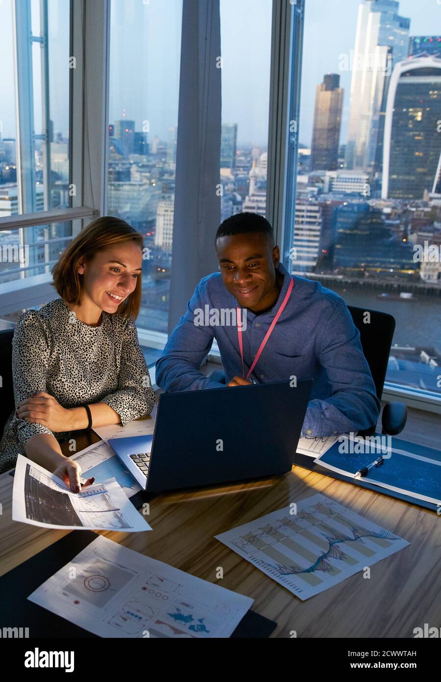 Uomini d'affari che lavorano in un computer portatile in un ufficio di alta altezza, Londra, Regno Unito Foto Stock