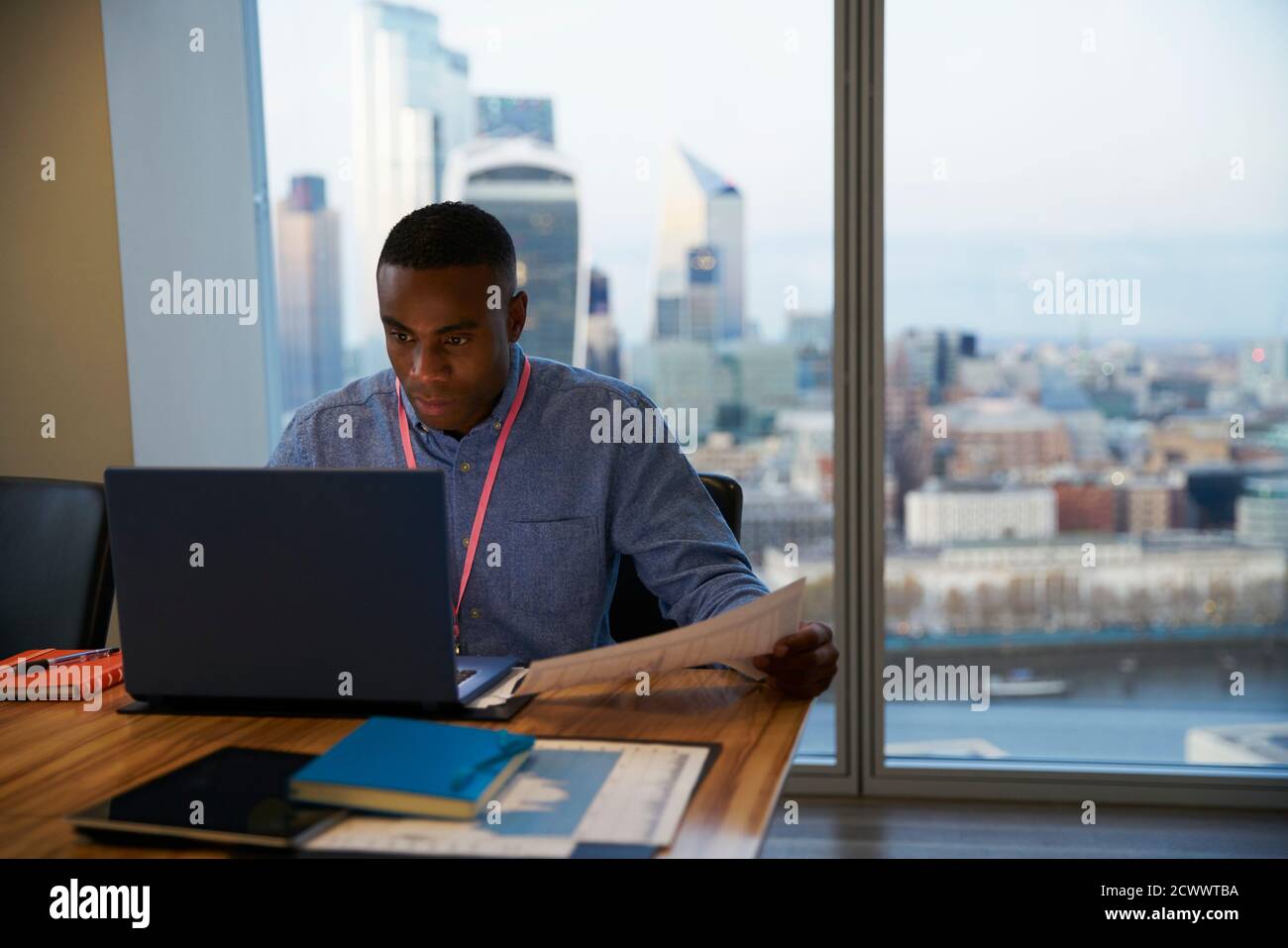 Uomo d'affari focalizzato che lavora su un computer portatile in un ufficio di alta altezza, Londra, Regno Unito Foto Stock