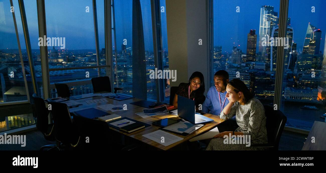 Uomini d'affari che lavorano tardi al laptop nell'ufficio di Highrise, Londra, Regno Unito Foto Stock