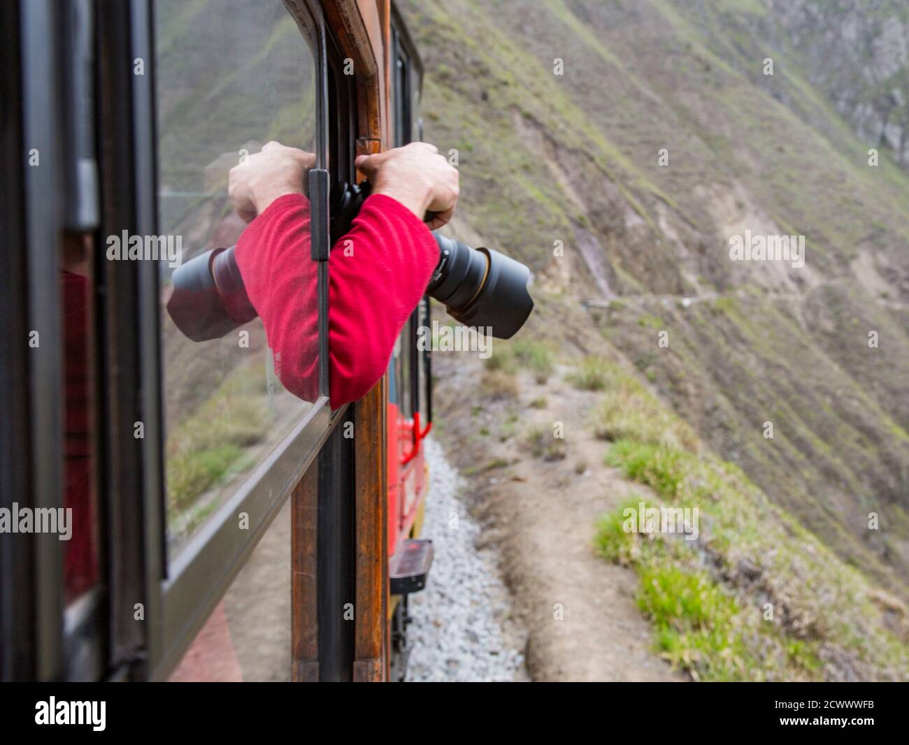Alausi, Ecuador - 17 Febbraio 2017 - Uomo gli blocca la testa e la fotocamera al di fuori della finestra del treno per ottenere l'immagine dell'avvolgimento paesaggio andino Foto Stock