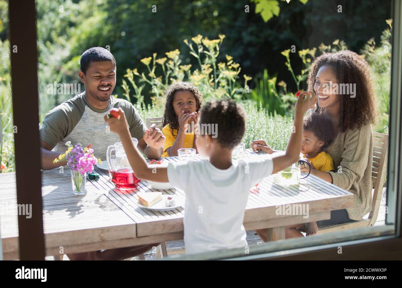 Buona famiglia gustando il pranzo in giardino sul luminoso patio estivo Foto Stock