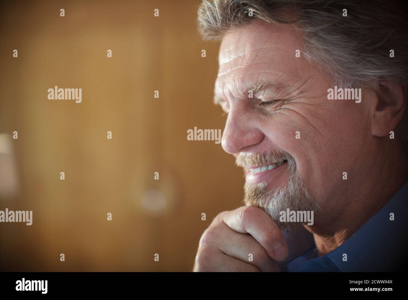 Primo piano sorridente uomo anziano con la mano sul mento Foto Stock