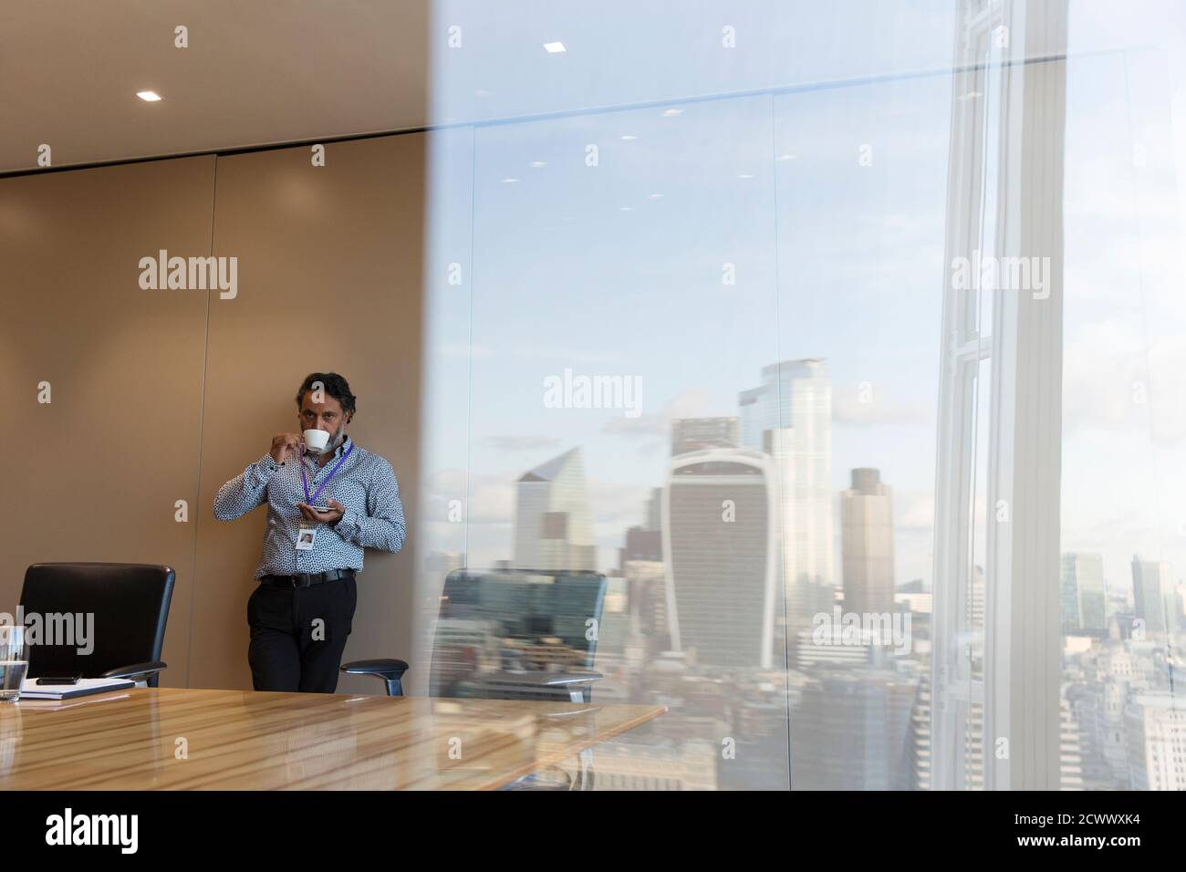 Uomo d'affari che beve caffè nella sala conferenze di alta altezza, Londra, Regno Unito Foto Stock