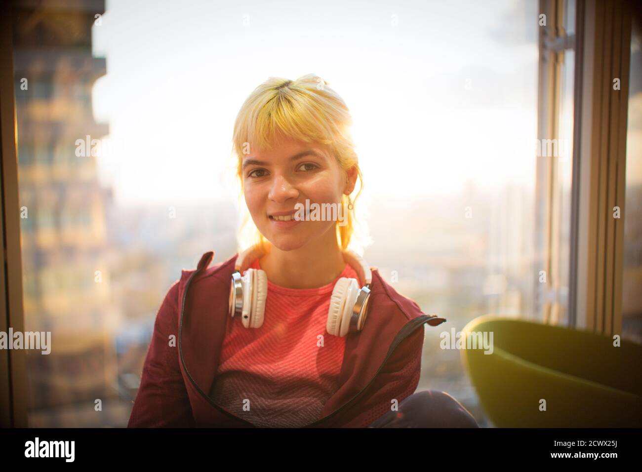 Giovane donna con un ritratto sicuro e le cuffie alla finestra Foto Stock