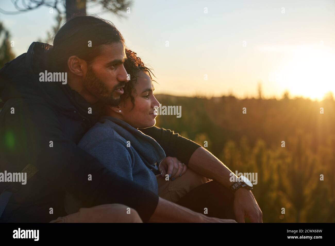 Affettuosa giovane coppia serena che si rilassa nella natura al tramonto Foto Stock