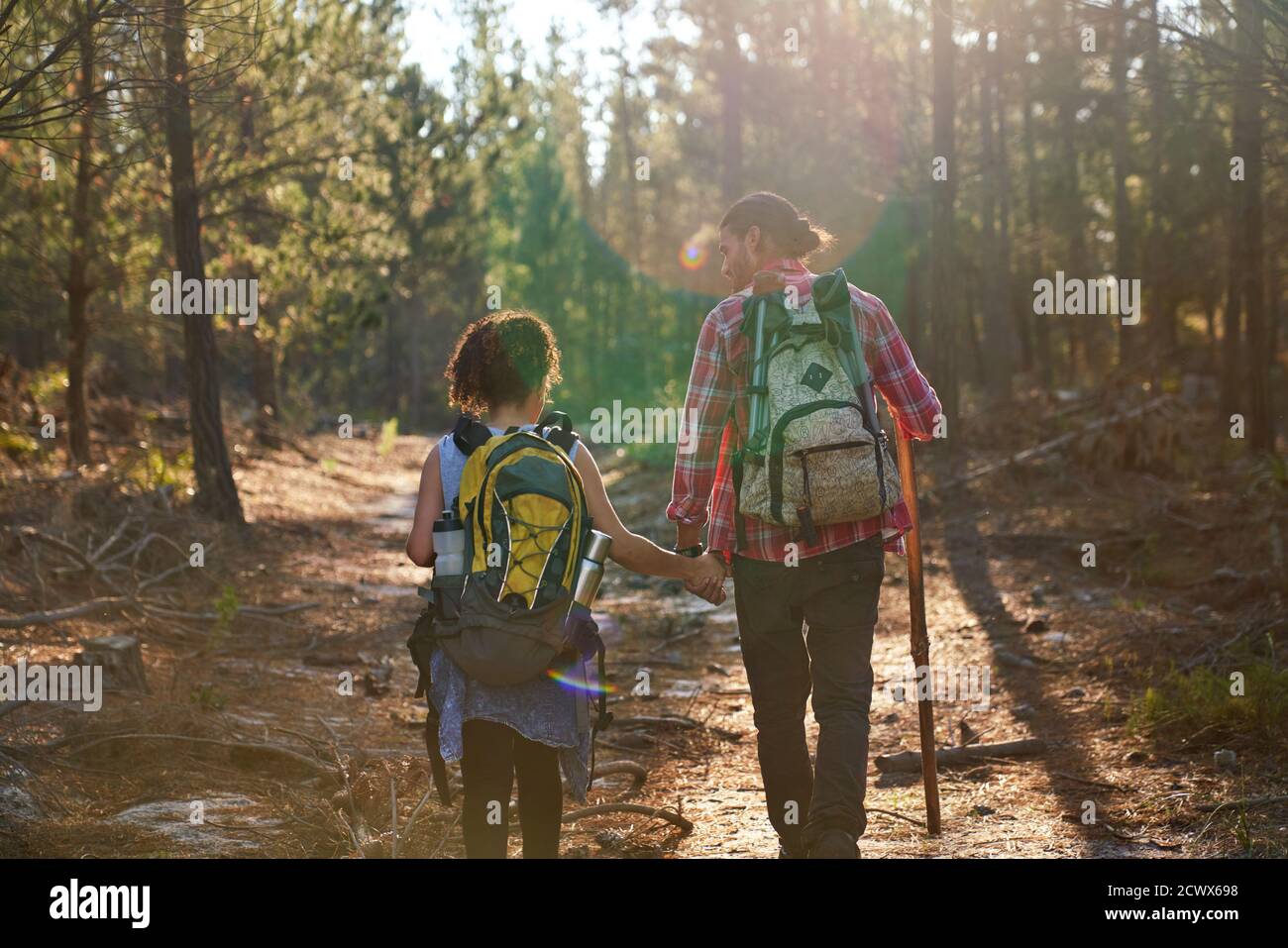 Giovane coppia trekking con zaini in soleggiati boschi estivi Foto Stock