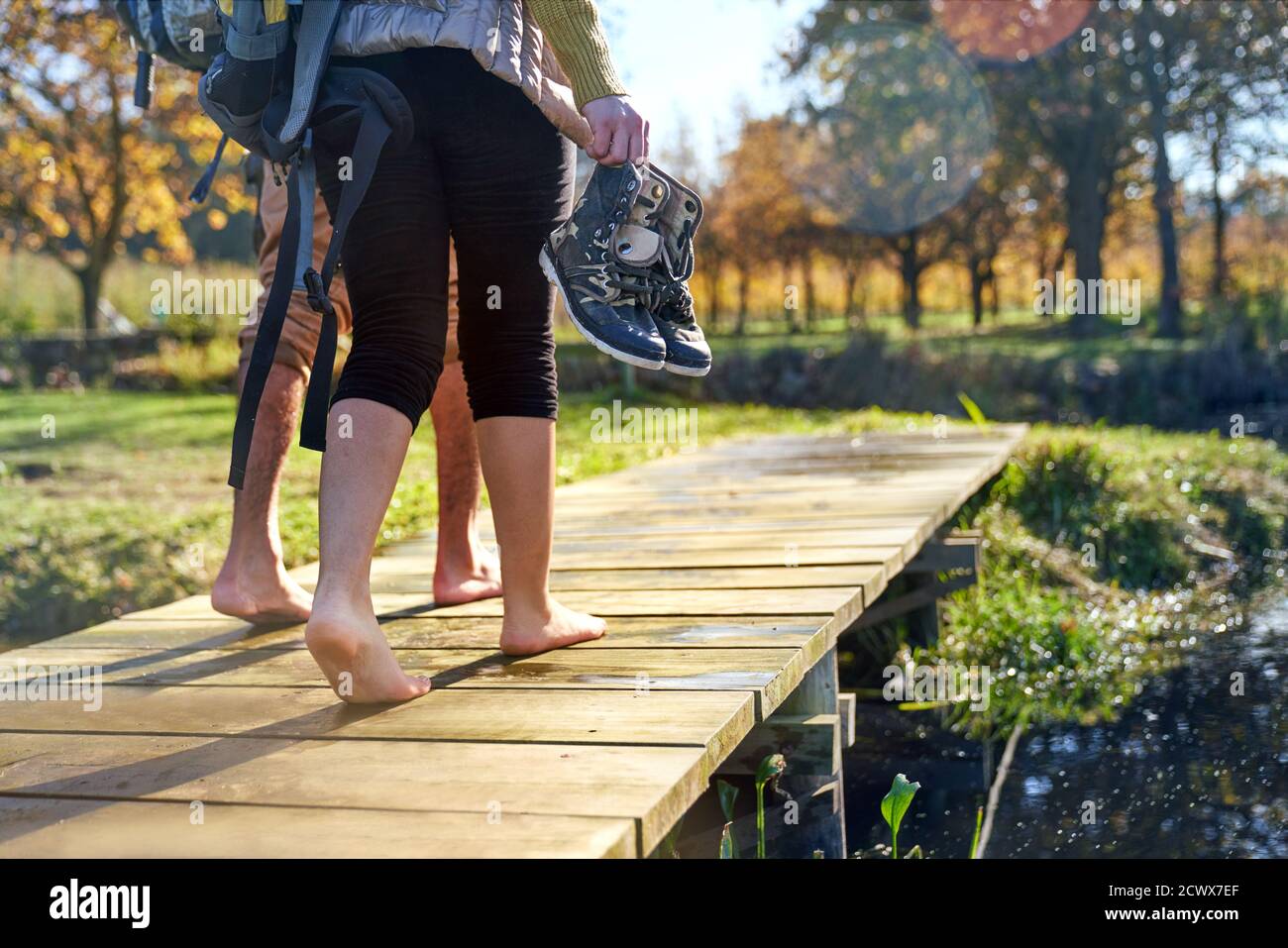Giovane coppia a piedi nudi che cammina sul soleggiato molo d'autunno Foto Stock