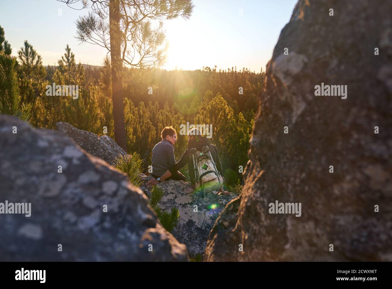 Affettuosa giovane coppia escursionista che si rilassa sulla roccia al tramonto soleggiato boschi Foto Stock