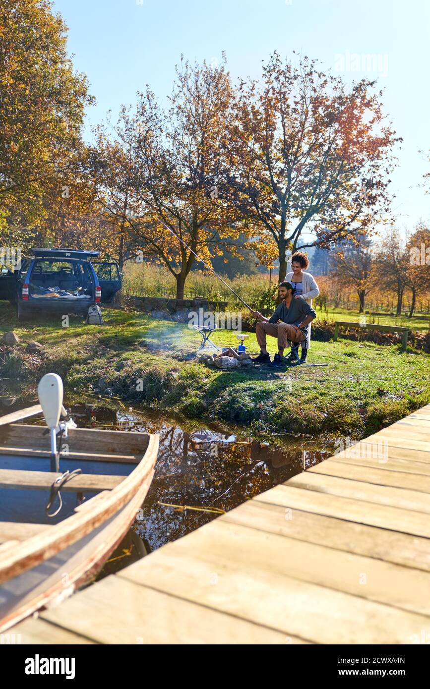 Giovane coppia in campeggio al sole autunno sul lago Foto Stock