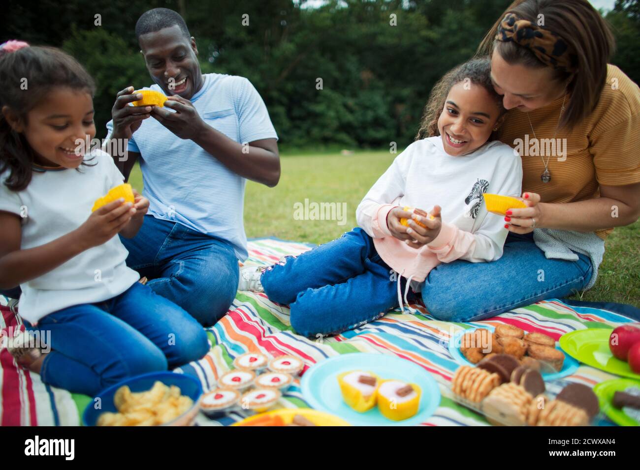 Buona famiglia gustando un dessert sulla coperta da picnic nel parco Foto Stock