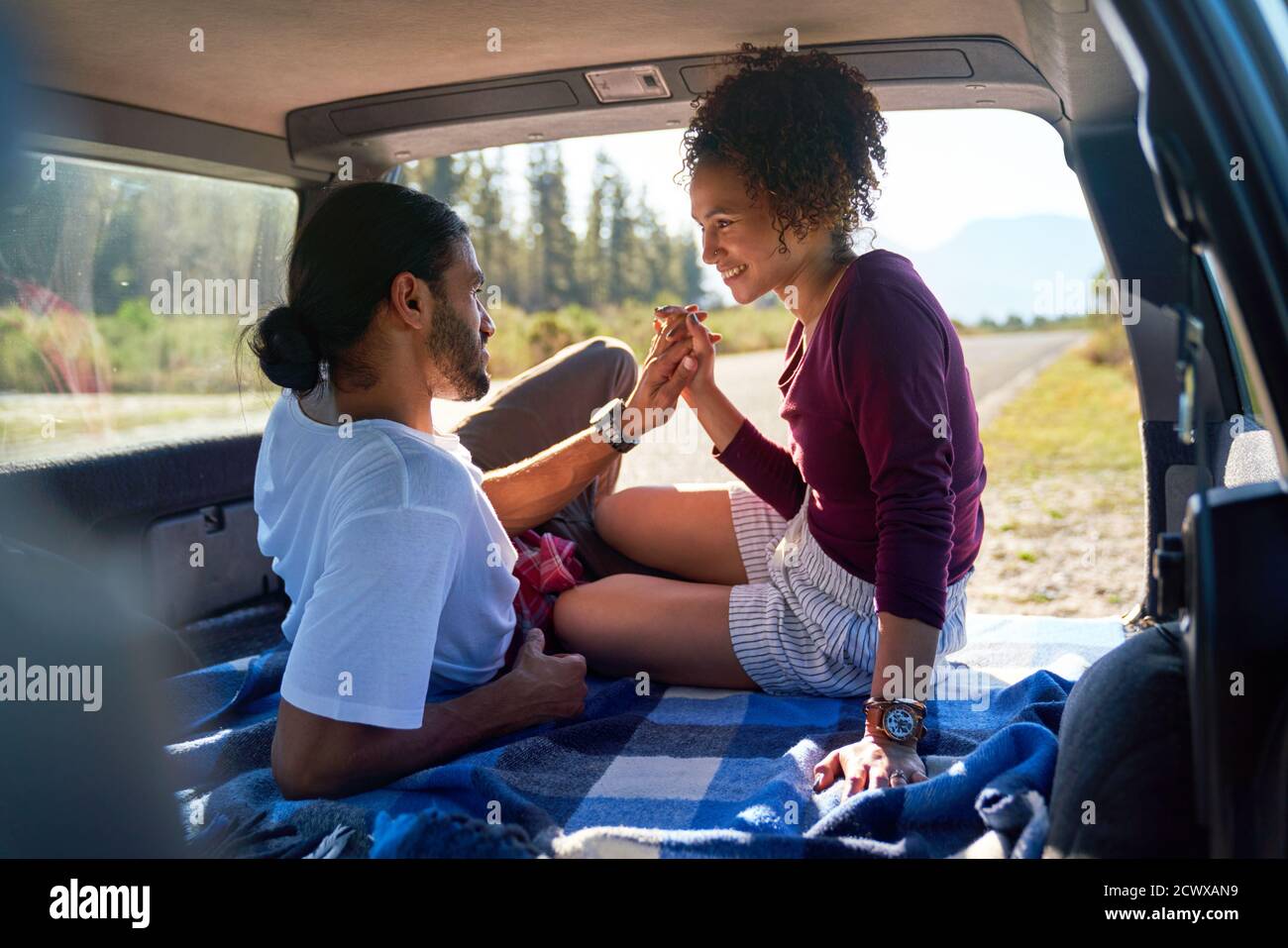 Felice affettuosa giovane coppia che tiene le mani dietro al sole auto Foto Stock