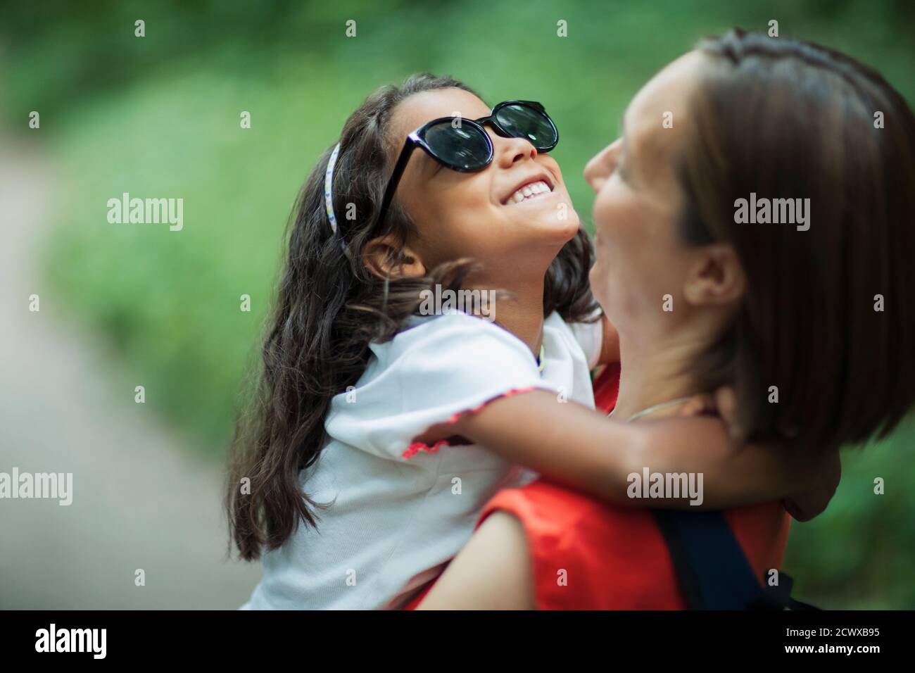 Madre felice che tiene la figlia in occhiali da sole Foto Stock