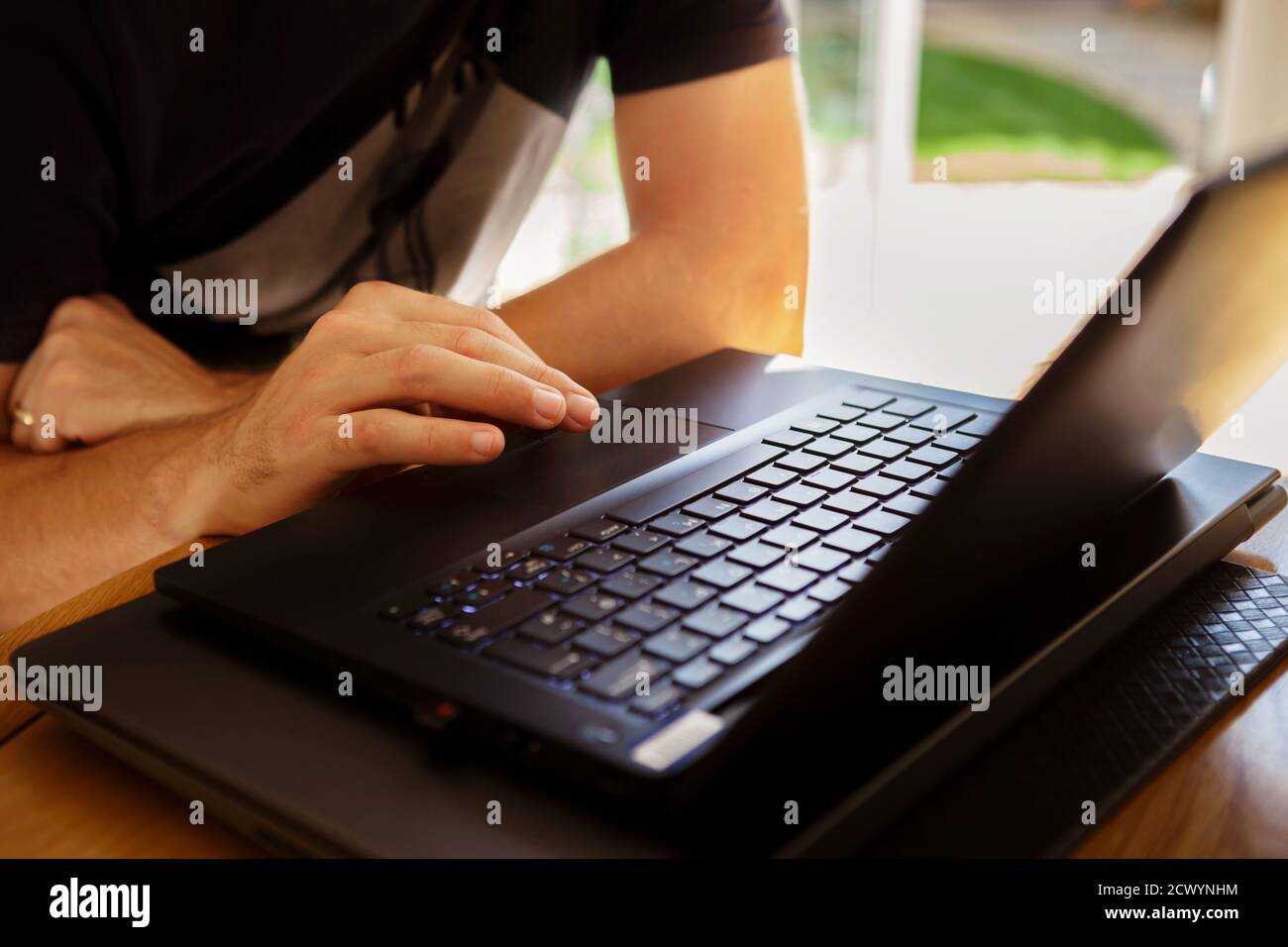 Primo piano di un uomo che dattilografa, lavorando da casa su un tavolo da cucina Foto Stock