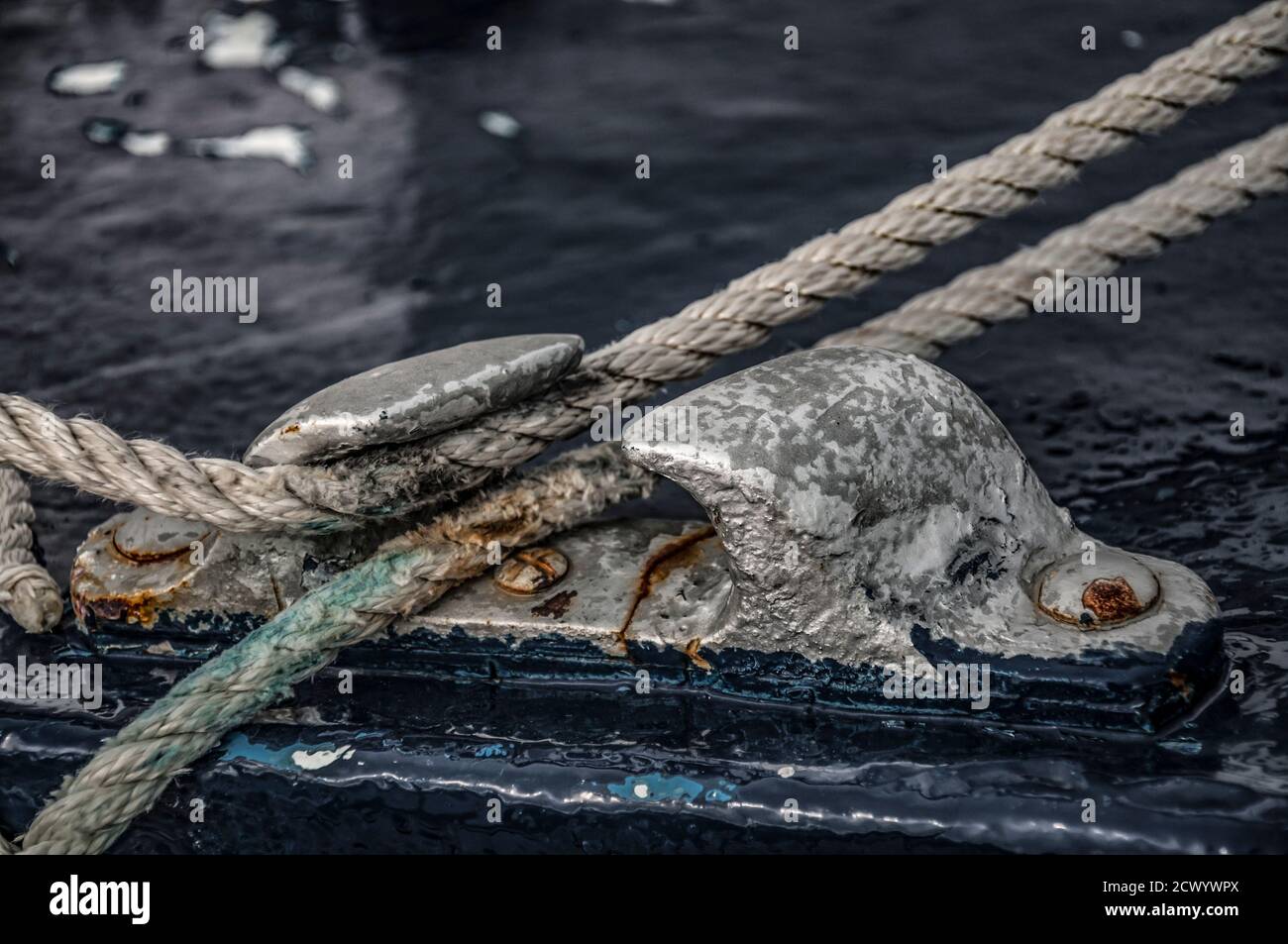 Primo piano del passacavo della barca con una corda che lo attraversa. Concetto visivo di collegamento come imbarcazione legata e collegata a un luogo sicuro. Foto Stock