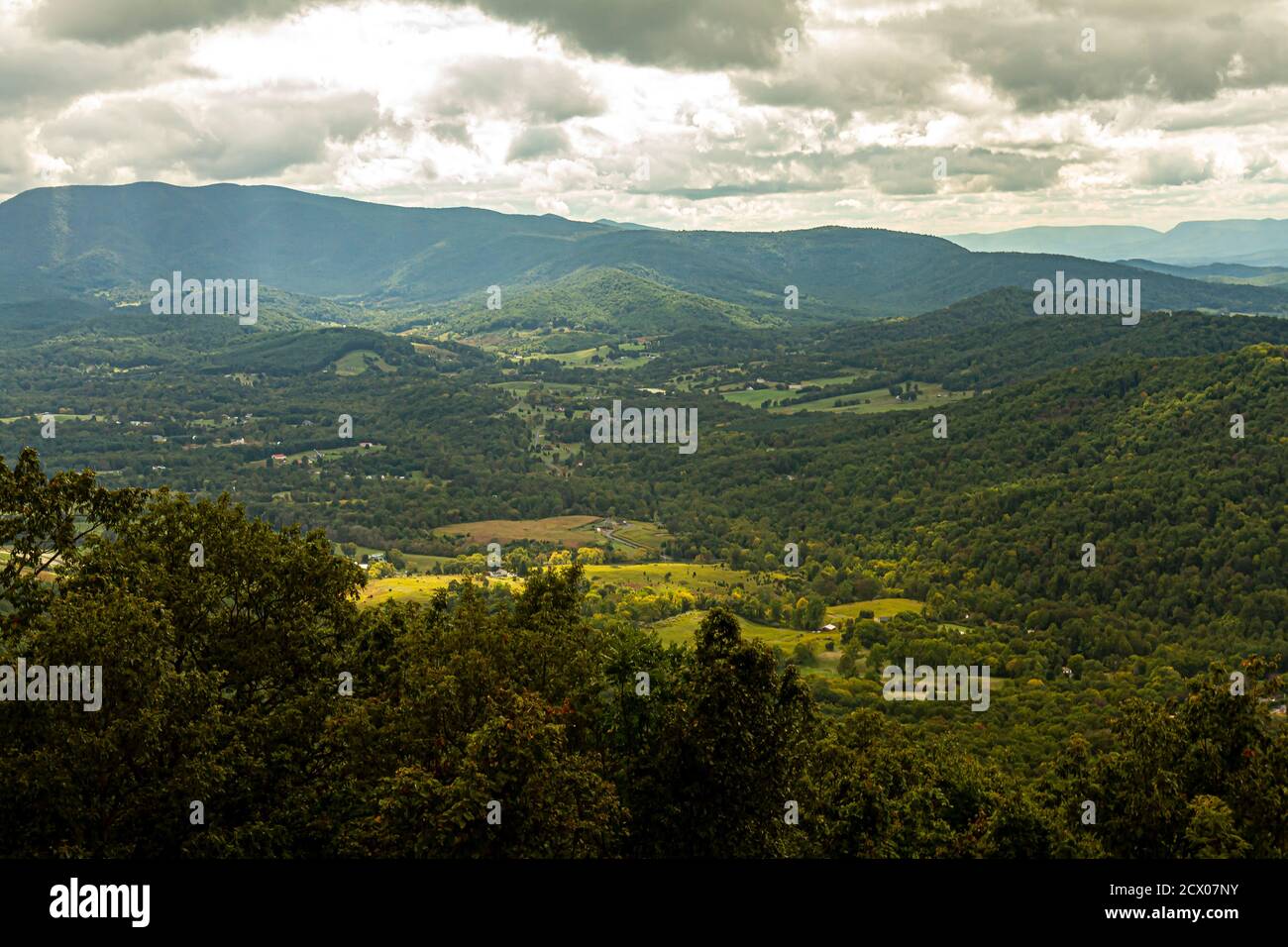 Una vista panoramica della Shenandoah Valley vista da un punto panoramico in Skyline Drive. I raggi di luce solare penetrano tra le nuvole e ci sono piccole fattorie wi Foto Stock