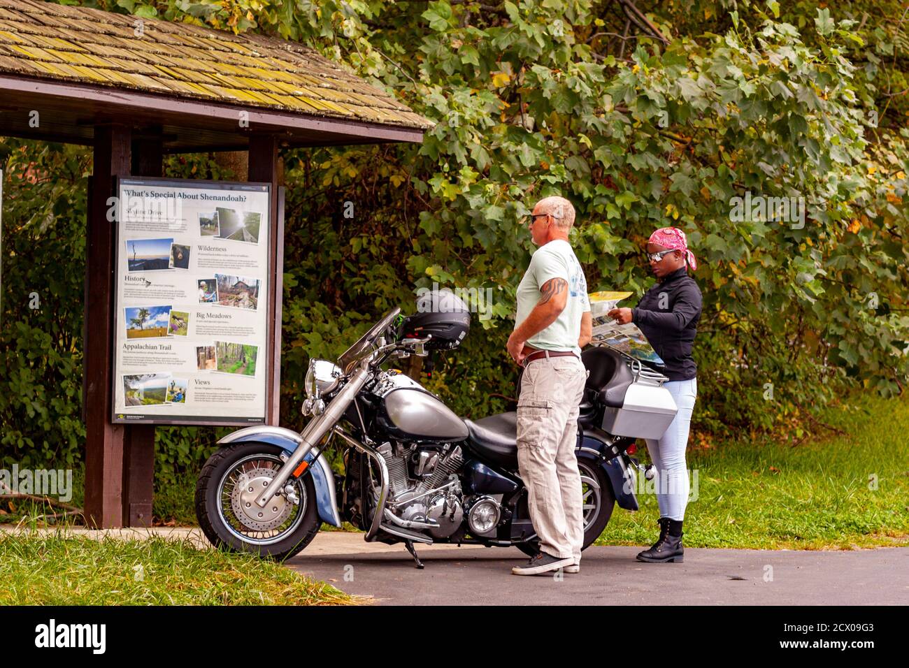 Shenandoah Valley, VA, USA 09/27/2020: Una coppia interracial (uomo caucasico anziano e donna afroamericana) sta in piedi dalla loro moto cercando Foto Stock