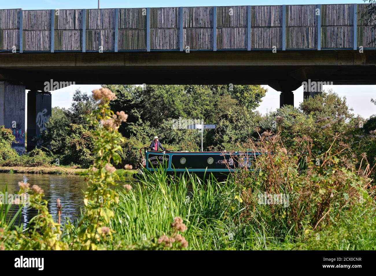 Una barca stretta canale che passa sotto l'autostrada M25 su Il canale di navigazione del fiume Wey a New Haw Surrey Inghilterra REGNO UNITO Foto Stock